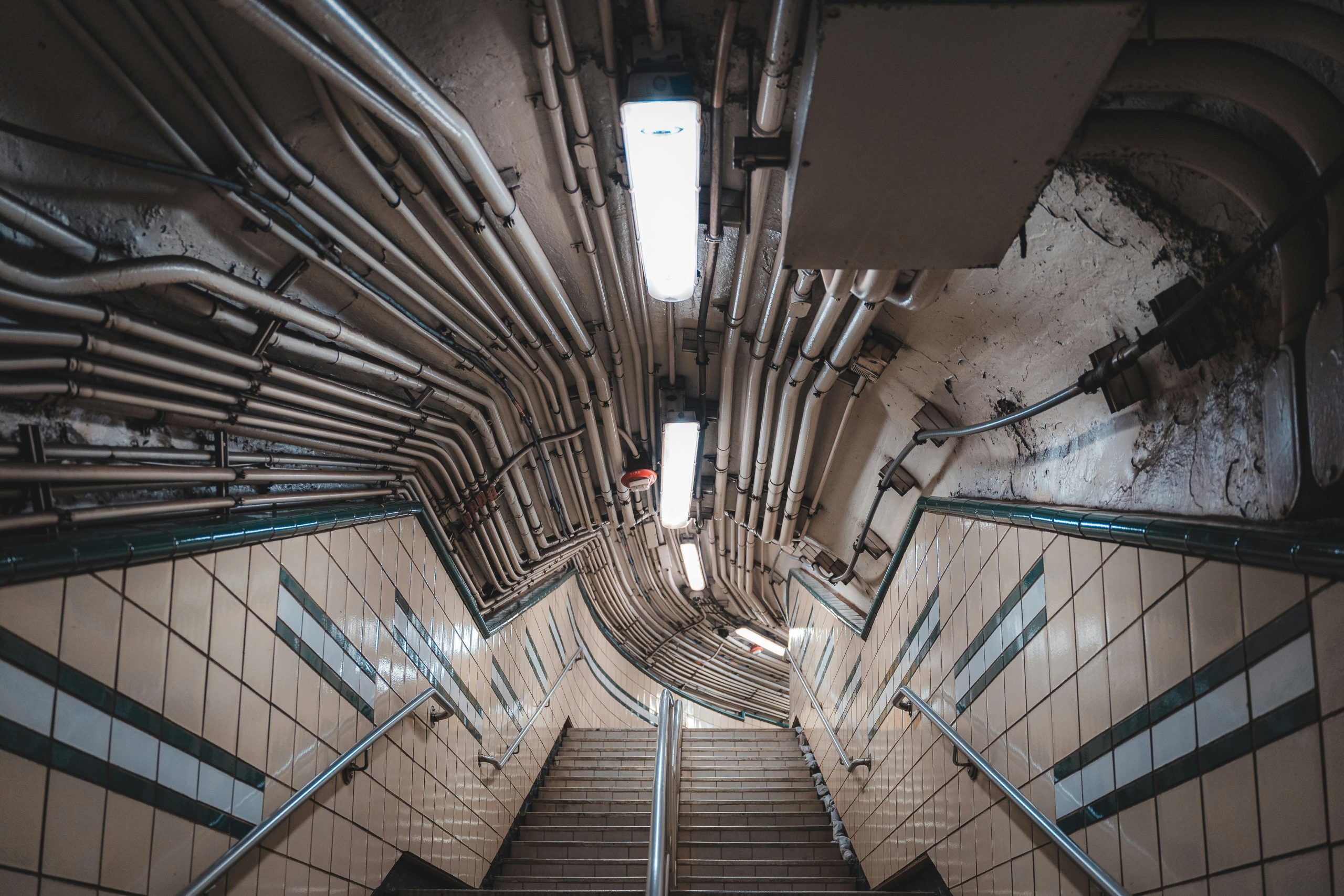 Dimly lit underground corridor with exposed wiring and tiled walls, capturing urban architecture.