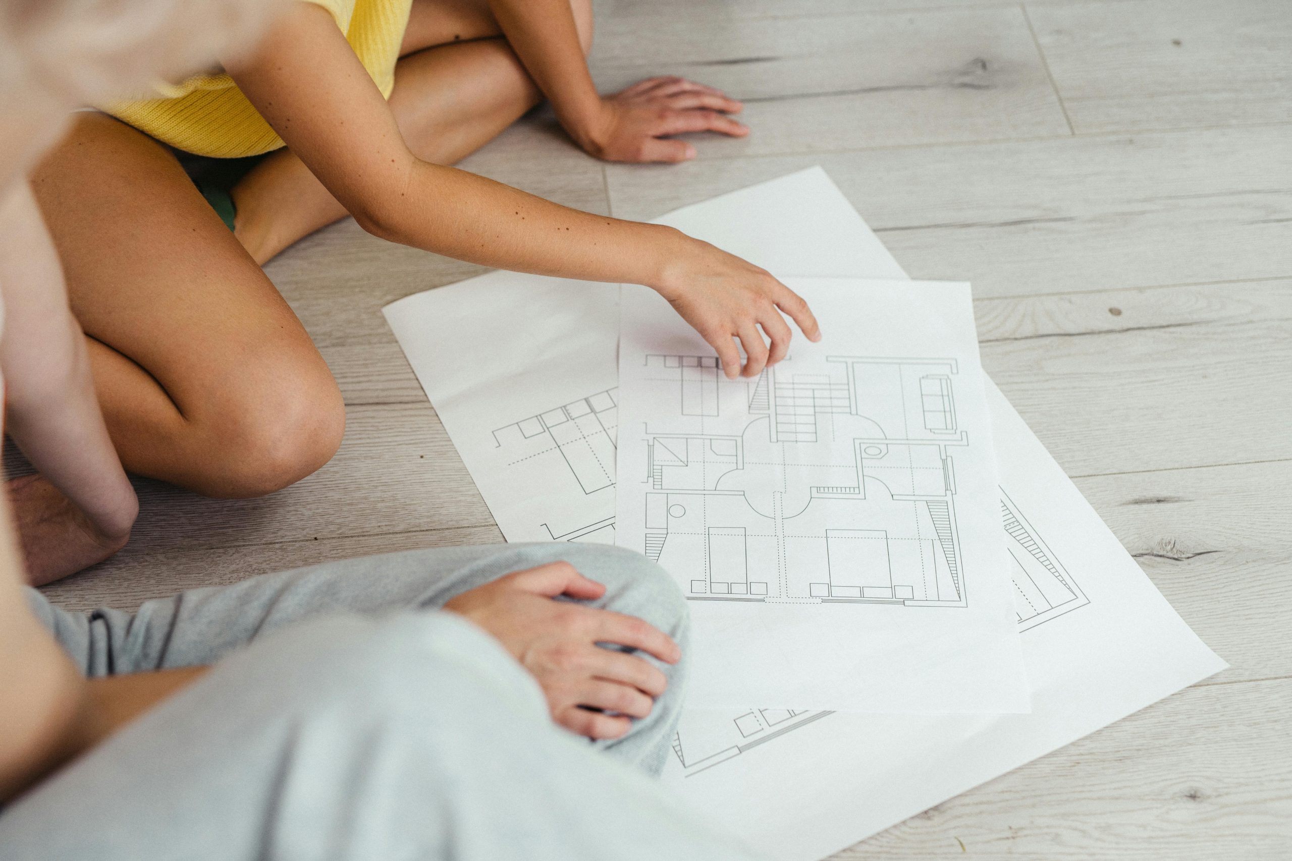 Adults review architectural blueprints indoors, focusing on floor design concepts.